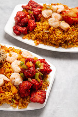 chinese food of sweet and sour chicken with fried rice, shrimp, pork ribs, on white plate with marble background