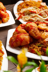 Chinese food of sweet and sour chicken with fried rice, shrimp, chop suey on brown wooden table