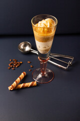 an italian  affogato coffee in a tall glass cup on a dark blue background, with coffee beans, ice cream scoop.