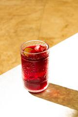Jamaica ice tea with a slide of lime on it, hard light of sunset, marble background