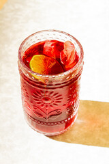 Jamaica ice tea with a slide of lime on it, hard light of sunset, marble background