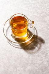 cup of hot tea in a cristal cup with sunset light, marble background.