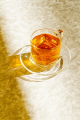 cup of hot tea in a cristal cup with sunset light, marble background.