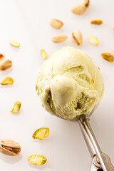 pistachio ice cream scoop with pistachio kernels on white background
