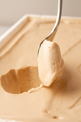 serving vanilla ice cream with spoon from a white bowl