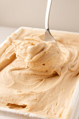serving vanilla ice cream with a spoon in white bowl, white background
