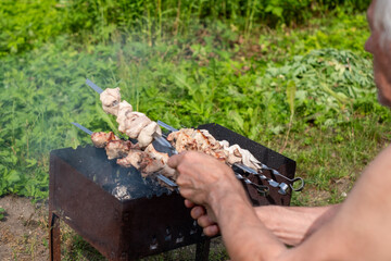 Grilling skewers with marinated meat in a lush backyard during a sunny day