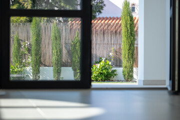 Modern interior view of a bright space showcasing a landscaped garden with tall cypress trees...