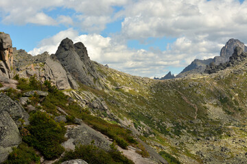 Intermountain saddle with high rock formations and steep slopes.