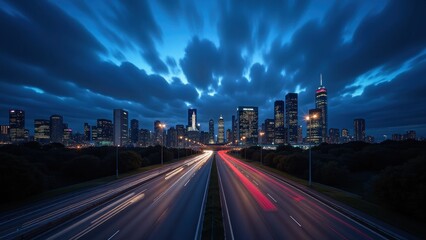 Obraz premium Night envelops the city skyline, stars peeking through towering skyscrapers' neon glow against a deep blue sky dotted with dramatic cumulonimbus clouds