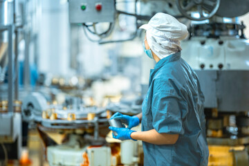 Inspector checking automated machinery in food production facility Focus on quality control safety and workflow efficiency. Worker overseeing food packaging machinery in a modern manufacturing plant.