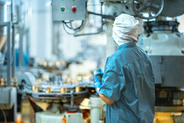 Inspector checking automated machinery in food production facility Focus on quality control safety and workflow efficiency. Worker overseeing food packaging machinery in a modern manufacturing plant.
