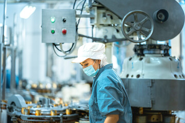 Inspector checking automated machinery in food production facility Focus on quality control safety and workflow efficiency. Worker overseeing food packaging machinery in a modern manufacturing plant.