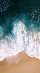 Aerial view of turquoise ocean waves crashing on a sandy beach.