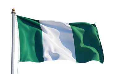 Nigeria’s national flag fluttering in the breeze with a bright blue sky behind it.
