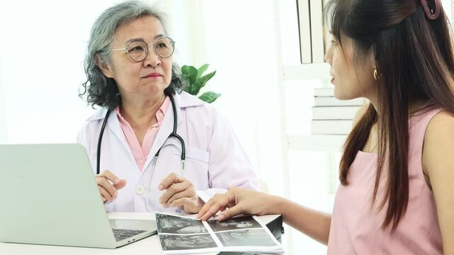 Senior doctor uses stethoscope to check fetus' health, measure fetal heart rate while moving and assess fetus and mother's health : Happy mother visits doctor before giving birth.