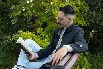 Hispanic man sitting in a park reading a book