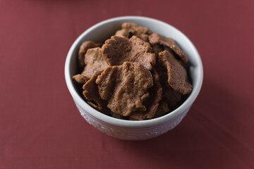 Overhead view of kuli-kuli in a white bowl, top view of nigerian groundnut cakes in a bowl, fresh homemade nigerian kulikuli in a ceramic bowl	