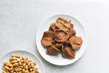 Overhead view of kuli-kuli on a white plate, top view of nigerian groundnut cakes on a plate, fresh homemade nigerian kulikuli on a ceramic plate