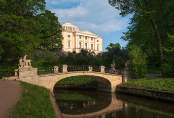 Obraz premium Centaur Bridge over the Slavyanka river against the background of the Pavlovsky Palace in the garden and park reserve Pavlovsky Park on a sunny summer day, Pavlovsk, St. Petersburg, Russia