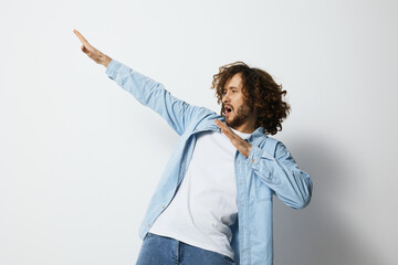 Young man with curly hair in a light blue shirt showcasing an expressive dance move against a...