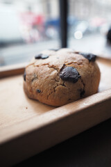 A Freshly Baked Chocolate Chip Cookie Sitting on a Wooden Tray