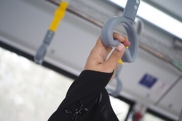 woman hand holding a gray handle on a bus