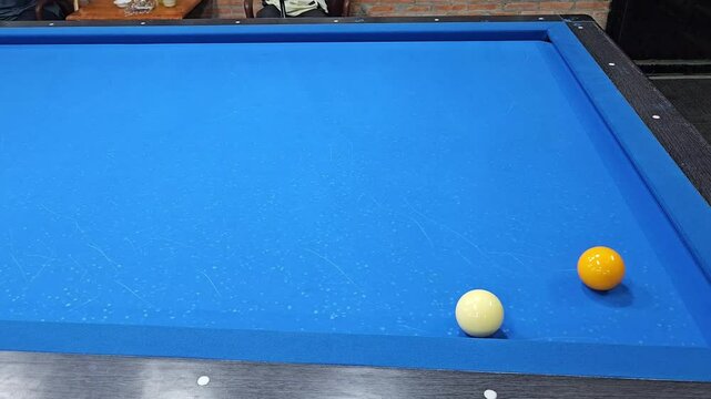 A person hit ball on the blue table of three cushion carom billiards.
