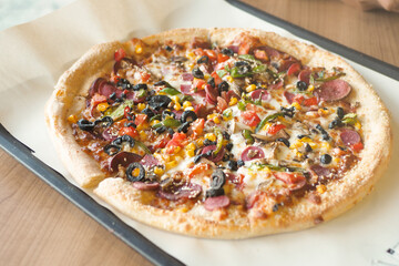 A Delicious Loaded Pizza with an Array of Toppings on a Wooden Table