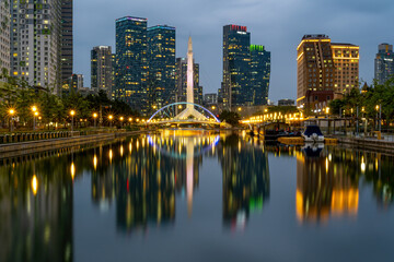 Songdo-dong, Yeonsu-gu, Incheon, South Korea - June 23, 2024: High angle and night view of Lake 1 Bridge on canal with water reflection at Central Park against apartments