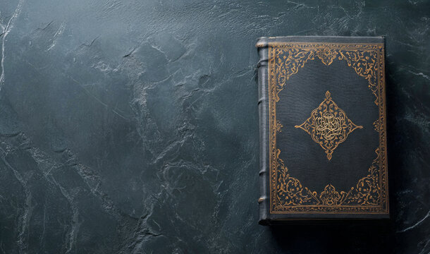 Ancient black coran book with golden decorations resting on dark stone surface