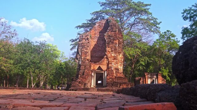 The ruins of an old castle built with laterite bricks of the ancient city of Si Thep.
Ancient Angkor Temple Tower Amidst Park's Historic Stone Ruins and Towering Trees 
in Si Thep Historical Park
