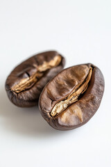 Close-up of two roasted coffee beans on a white background, highlighting their rich brown color and textured surface.