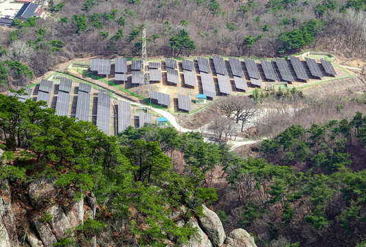Namwon-si, Jeollabuk-do, South Korea - February 27, 2024: High angle view of pine trees on the rock at Pungaksan Mountain against collector plates and transmission tower
