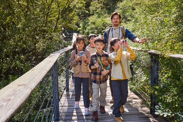 Happy teacher and kids hiking in the mountains