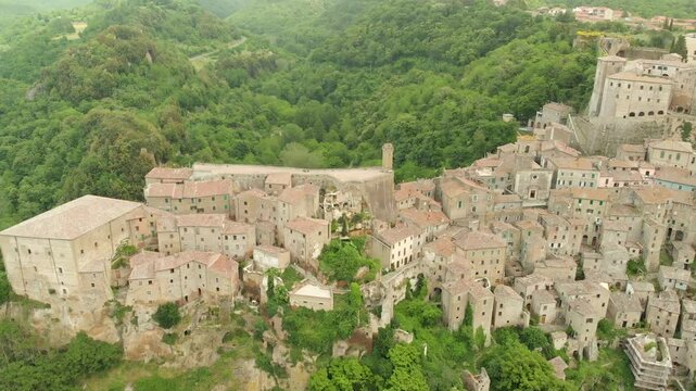 Aerial summer afternoon view of Sorano. Rooftops of an ancient medieval hill town hanging from a tuff stone over the Lente River. Etruscan heritage. Province Grosseto, Tuscany, Italy.
