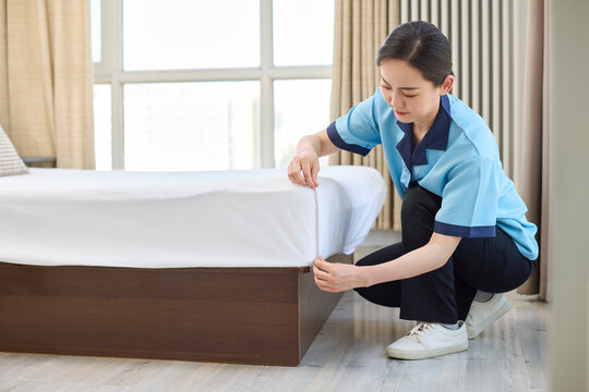 Female cleaner tidying the bed
