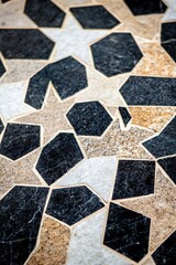 A detailed close-up of a stone mosaic featuring intricate geometric patterns