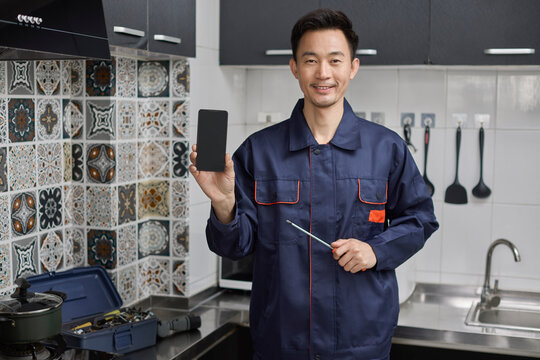 Handyman holding a screwdriver and smart phone in the kitchen