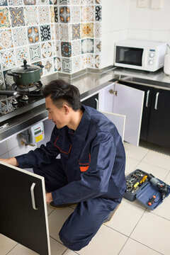 Handyman repairing the kitchen cabinet