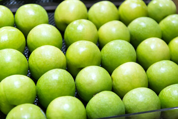 Fresh green apples arranged neatly in the supermarket