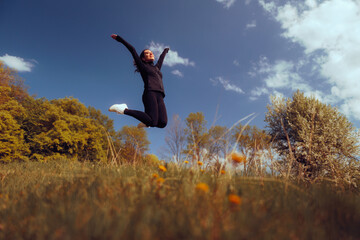 Happy Excited Woman Jumping in a Beautiful Meadow. Cheerful carefree person feeling enthusiastic and free spirited in nature
