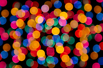 Close-up color  photo of soft, blurred de-focused vibrant multi-colored circles against a black background.