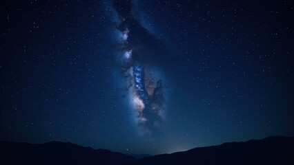 A mesmerizing, wide-angle vista captures the Milky Way arching majestically across a star-studded, deep blue night sky. Tiny specks of light punctuate the expanse, inviting endless wonder and explorat