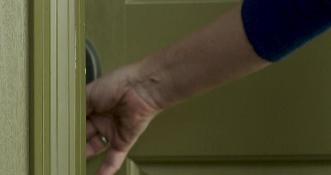 Woman's hand with diamond ring unlocking front door and entering