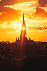 Fototapeta premium A stunning church silhouette against a vibrant sunset sky, with dramatic clouds casting a warm glow over the scene.