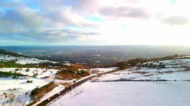 Aerial shot of Cavehill in Belfast, Northern Ireland on a snowy and calm winter day. The camera moves right to left, over the mountains and passing cars. Shot in 4K, 60fps and in Rec709 color.