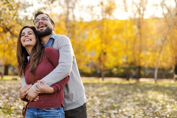 Joyful couple hugging and enjoying togetherness in city park. Copy space.