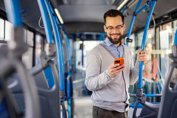 Portrait of passenger with cellphone in hand riding bus and buying bus ticket online on mobile app.