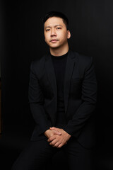 Fototapeta premium a man in a black suit sitting on a chair